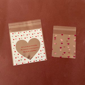 May include: Two clear plastic bags with a heart pattern. The larger bag has a heart-shaped window with the text "You've got that special something. That makes you someone very special. Thanks for everything!" printed inside.