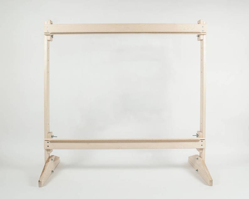 May include: A wooden loom stand with a rectangular frame and two legs on each side. The stand is made of light wood and has a natural finish.