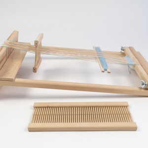 May include: A wooden loom with a blue and multi-colored yarn warp and a separate wooden heddle.