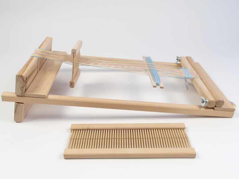 May include: A wooden loom with a blue and multi-colored yarn warp and a separate wooden heddle.