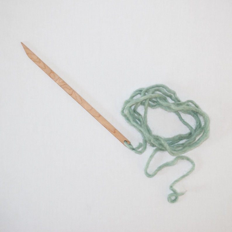 Peut inclure: Une aiguille en bois avec un trou &agrave; l'extr&eacute;mit&eacute; et une pelote de fil vert clair.