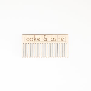 May include: A wooden comb with the text "oake & ashe" engraved on the top.
