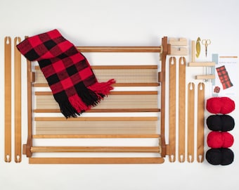 May include: A wooden loom with red and black yarn, a red and black plaid scarf, and instructions for making a buffalo check scarf.