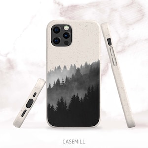 May include: A white phone case with a black and white image of a foggy forest. The case is made of a sustainable material and has a raised camera bump.