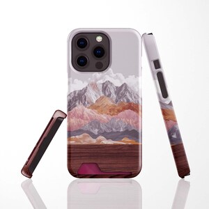 May include: A phone case with a mountain landscape design. The case features a wood-grain texture at the bottom, transitioning to a scene of layered mountains in shades of pink, orange, and gray. The case is shown in multiple pieces.