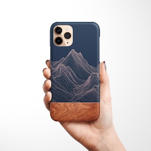 May include: A navy blue phone case with a wood accent and a line drawing of mountains in a light pink color.
