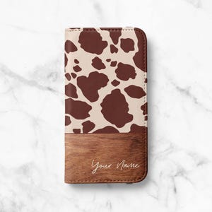 Könnte beinhalten: Eine Handyhülle mit einem Kuhmuster in Braun und Creme. Der untere Teil hat ein Holzmaserungsmuster mit dem kursiven Text "Your Name".