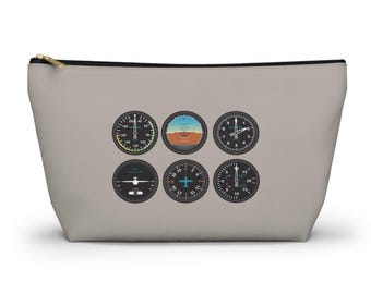 May include: A gray zippered pouch with six black and white airplane instrument gauges printed on it. The gauges include an altimeter, airspeed indicator, heading indicator, vertical speed indicator, attitude indicator, and a turn coordinator.