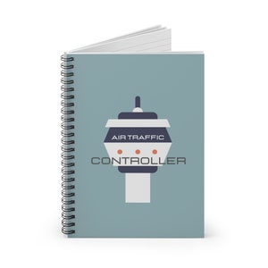 Puede incluir: Una libreta espiral azul con una ilustración blanca y gris de una torre de control de tráfico aéreo. La torre tiene el texto "AIR TRAFFIC CONTROLLER".