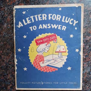 May include: A vintage children's book cover with a blue background and white stars. The title is "A Letter for Lucy to Answer" with a girl writing a letter at a desk. The book is part of the "Follett Picture Stories for Little Folks" series.