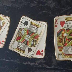May include: Three rectangular ceramic trays designed to resemble playing cards. Each tray features a king face card illustration with gold-toned edges. The designs include the King of Diamonds, King of Spades, and King of Hearts, each layered over a secondary card.