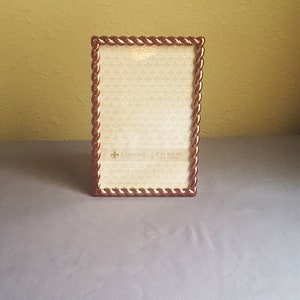 May include: A brown picture frame with a rope-like design around the edge. The frame is 4 inches by 6 inches and has a white mat.