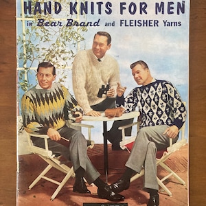 Puede incluir: Una portada de libro vintage con tres hombres que llevan jerséis, sentados en sillas alrededor de una mesa. La portada se titula "Hand Knits for Men in Bear Brand and Fleisher Yarns" y tiene el número de volumen y el precio: "vol. 56 75¢".