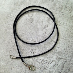 May include: A black leather cord necklace with a silver clasp. The cord is approximately 50 cm long.