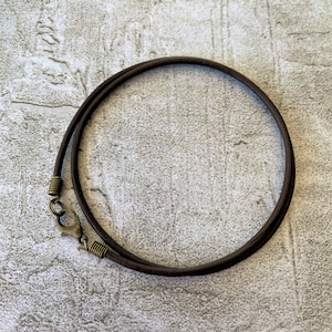 May include: A brown leather cord necklace with a brass clasp.