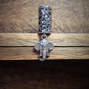 May include: Silver hair tie with an intricate design and an elephant charm.