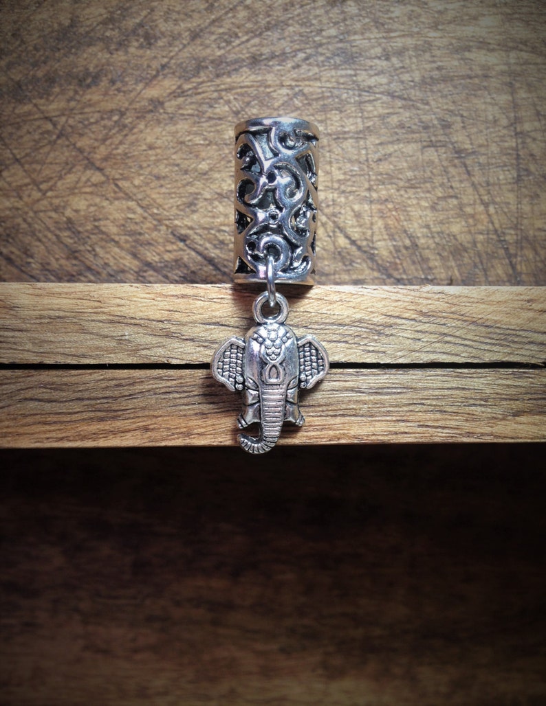 May include: Silver hair tie with an intricate design and an elephant charm.