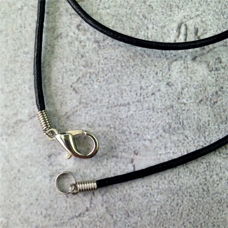 May include: A black leather cord necklace with a silver clasp and a silver jump ring.
