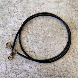 May include: A black leather cord necklace with a bronze clasp and spring ring.