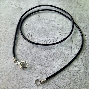 May include: A black leather cord necklace with a silver clasp and jump ring.