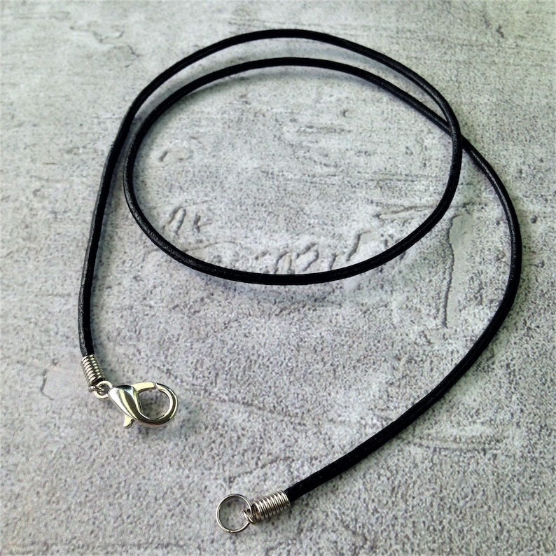 May include: A black leather cord necklace with a silver clasp and jump ring.