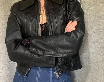 May include: A black leather jacket with a zipper closure and a Harley Davidson logo patch on the left sleeve.