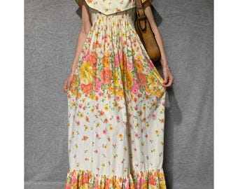 May include: A white maxi dress with a floral print in shades of pink, orange, and yellow. The dress has a ruffled neckline, short sleeves, and a gathered waist. The skirt is full and flowing, with a ruffled hem.