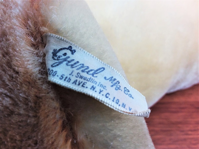 May include: White fabric label with blue text that reads " Gund Mfg. Co. J. Swedlin Inc. 200-5th Ave. N.Y.C. 10, N.Y."