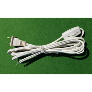 May include: A white electrical cord with a dimmer switch and a two-prong plug. The cord is coiled and tied, with exposed wires at one end. The background is a solid green color.