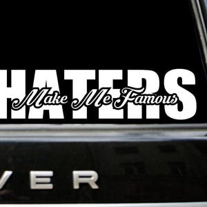 Puede incluir: Calcomanía de vinilo blanco con el texto "HATERS Make Me Famous" en una ventana de coche negro.