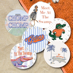May include: A collection of round coasters with various designs. One coaster features a football field with "CHOMP CHOMP" text. Other coasters have "Meet Me At The Swamp", "Gators" text, and alligator illustrations. The coasters are decorated with faux pearls.