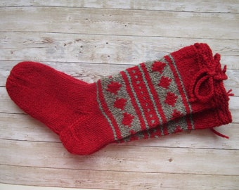 May include: Red and gray knitted socks with a heart pattern. The socks have a decorative bow at the top.