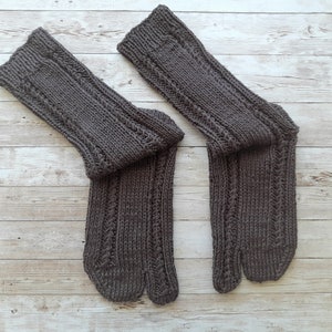 Peut inclure: Une paire de chaussettes en tricot marron avec un design à bout fendu. Les chaussettes sont faites avec un motif en tricot torsadé.