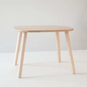 May include: A light wood children's table with a rectangular top and four rounded legs.