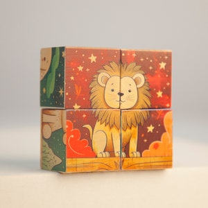 May include: A wooden puzzle cube featuring a friendly lion illustration. The cube has a warm color palette with a red and orange background, stars, and other animal illustrations. The cube is made of wood.