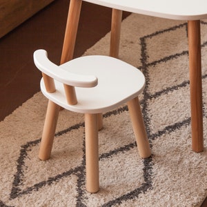 K&ouml;nnte beinhalten: Kleiner wei&szlig;er Holzstuhl mit geschwungener R&uuml;ckenlehne und vier Beinen. Der Stuhl ist Teil eines Kinderm&ouml;belsets mit Beinen aus Naturholz und einer wei&szlig;en Sitzfl&auml;che und R&uuml;ckenlehne. Der Stuhl ist f&uuml;r Kinder konzipiert.