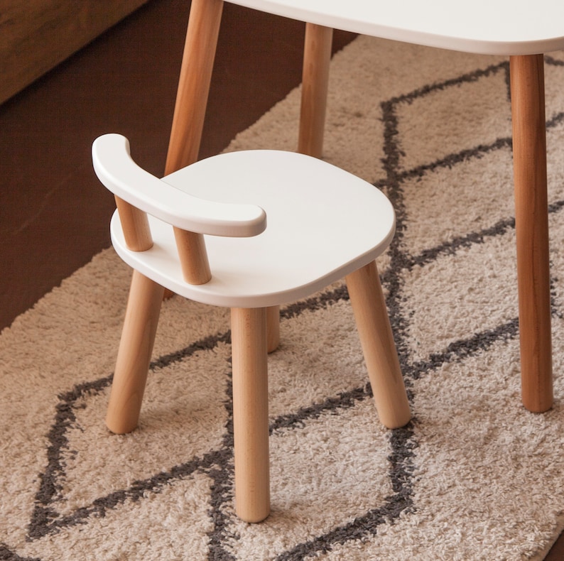 K&ouml;nnte beinhalten: Kleiner wei&szlig;er Holzstuhl mit geschwungener R&uuml;ckenlehne und vier Beinen. Der Stuhl ist Teil eines Kinderm&ouml;belsets mit Beinen aus Naturholz und einer wei&szlig;en Sitzfl&auml;che und R&uuml;ckenlehne. Der Stuhl ist f&uuml;r Kinder konzipiert.