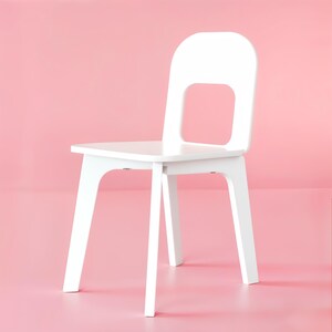 May include: A white wooden chair featuring a smooth, matte finish, a flat square seat, and a tall backrest with a large, rectangular cutout in the center. The chair is supported by four straight, sturdy legs angled slightly outward for stability.