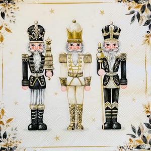May include: Three decorative nutcracker figures in black, white, and gold. The nutcrackers are dressed in ornate uniforms and hold a tree, staff, and scepter. The background is a cream colour with gold stars and floral accents.