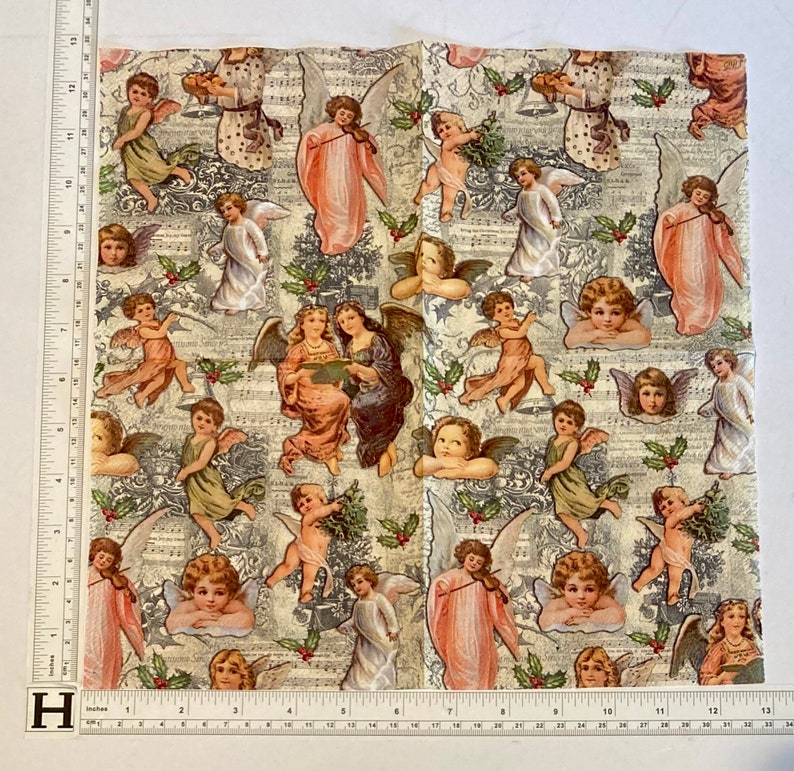 Puede incluir: Una tela blanca con un patr&oacute;n repetitivo de &aacute;ngeles tocando instrumentos musicales y cantando. Los &aacute;ngeles est&aacute;n representados en una variedad de poses y visten t&uacute;nicas blancas y doradas. La tela est&aacute; decorada con hojas de acebo y bayas.