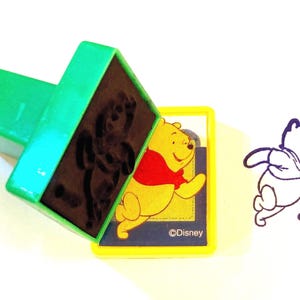 Sello autoentintable de Disney Winnie the Pooh corriendo, 1" x 1 1/4" con mango de 1"