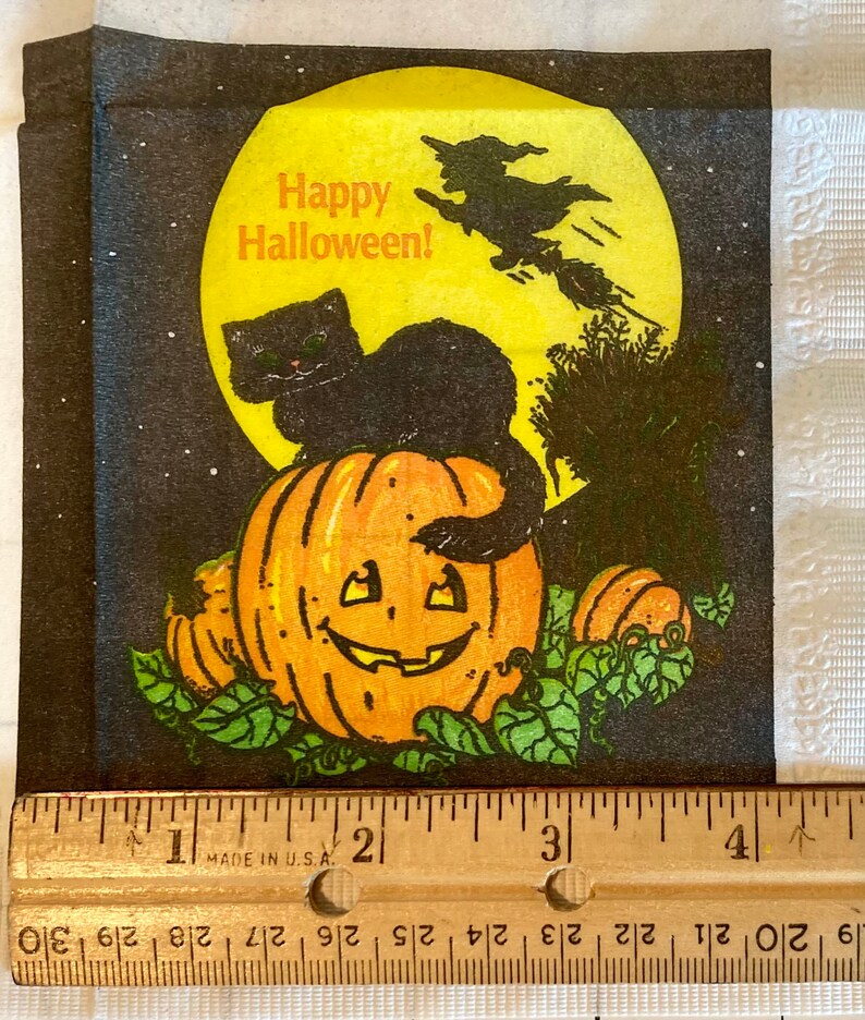 May include: A black cat sits on top of a jack-o'-lantern with a witch flying in the background. The moon is yellow and the background is black with white stars. The text "Happy Halloween!" is written in orange.