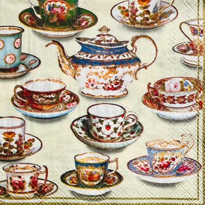 May include: A collection of vintage teacups and saucers with a teapot on a cream-colored background. The teacups feature floral and fruit designs in various colors, including red, blue, green, and gold. The teapot has a blue and gold rim with floral patterns.