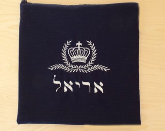 May include: A dark blue velvet bag with a zipper closure. The bag features a silver embroidered crown with a wreath and the Hebrew word "Ha'rei" in silver thread.