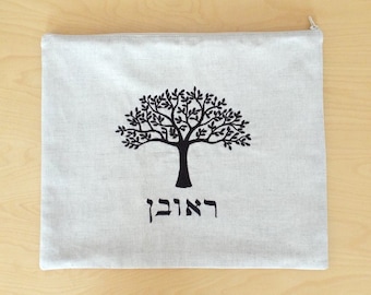 May include: A white linen bag with a black embroidered tree and the Hebrew word "Chai" underneath. The bag has a zipper closure.