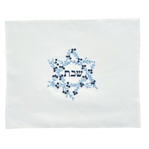 Könnte beinhalten: Weißer Leinen-Challah-Überzug mit gesticktem Davidstern in Blau und Marineblau mit dem hebräischen Wort "Shabbat" in der Mitte.