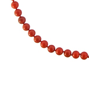 May include: A strand of red coral beads, strung together on a thin cord.