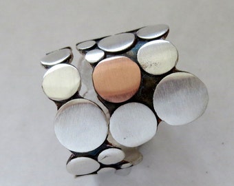 Sterling silver ring with a cercle copper or brass on top. Oxidized. Adjustable. 100% hand made. Unisex ring