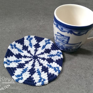 Könnte beinhalten: Ein blauer und weißer gehäkelter Untersetzer mit einem runden Design. Der Untersetzer liegt auf einer grauen Oberfläche neben einer blauen und weißen Keramiktasse.
