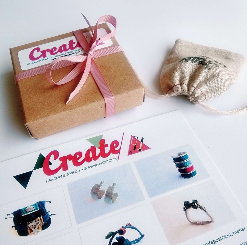 May include: A brown cardboard box tied with a pink ribbon, a small drawstring bag, and a brochure featuring the word "Create" in pink and red. The brochure showcases handmade jewellery.